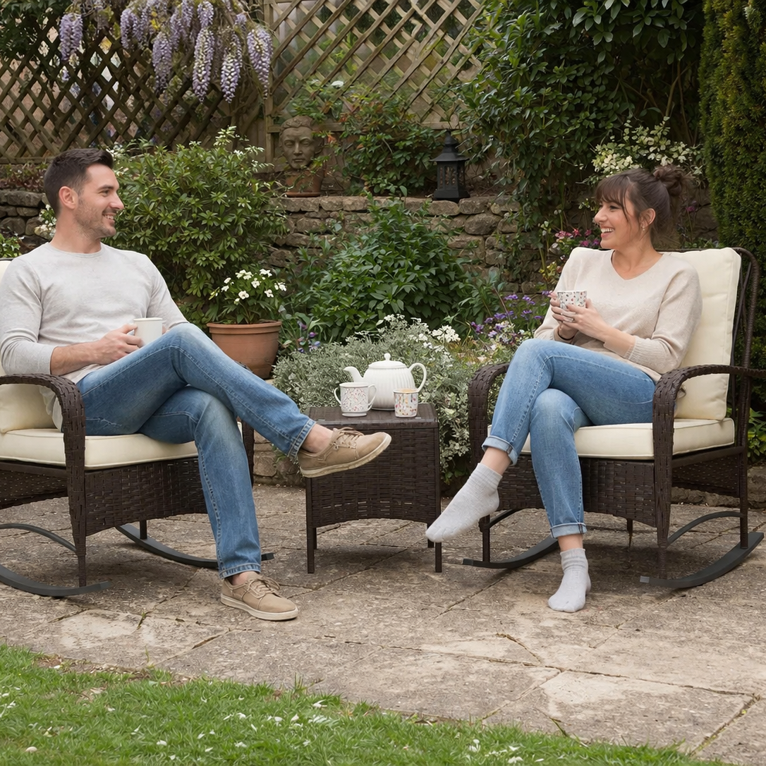 Two people sitting in wicker chairs in a garden setting, enjoying tea.